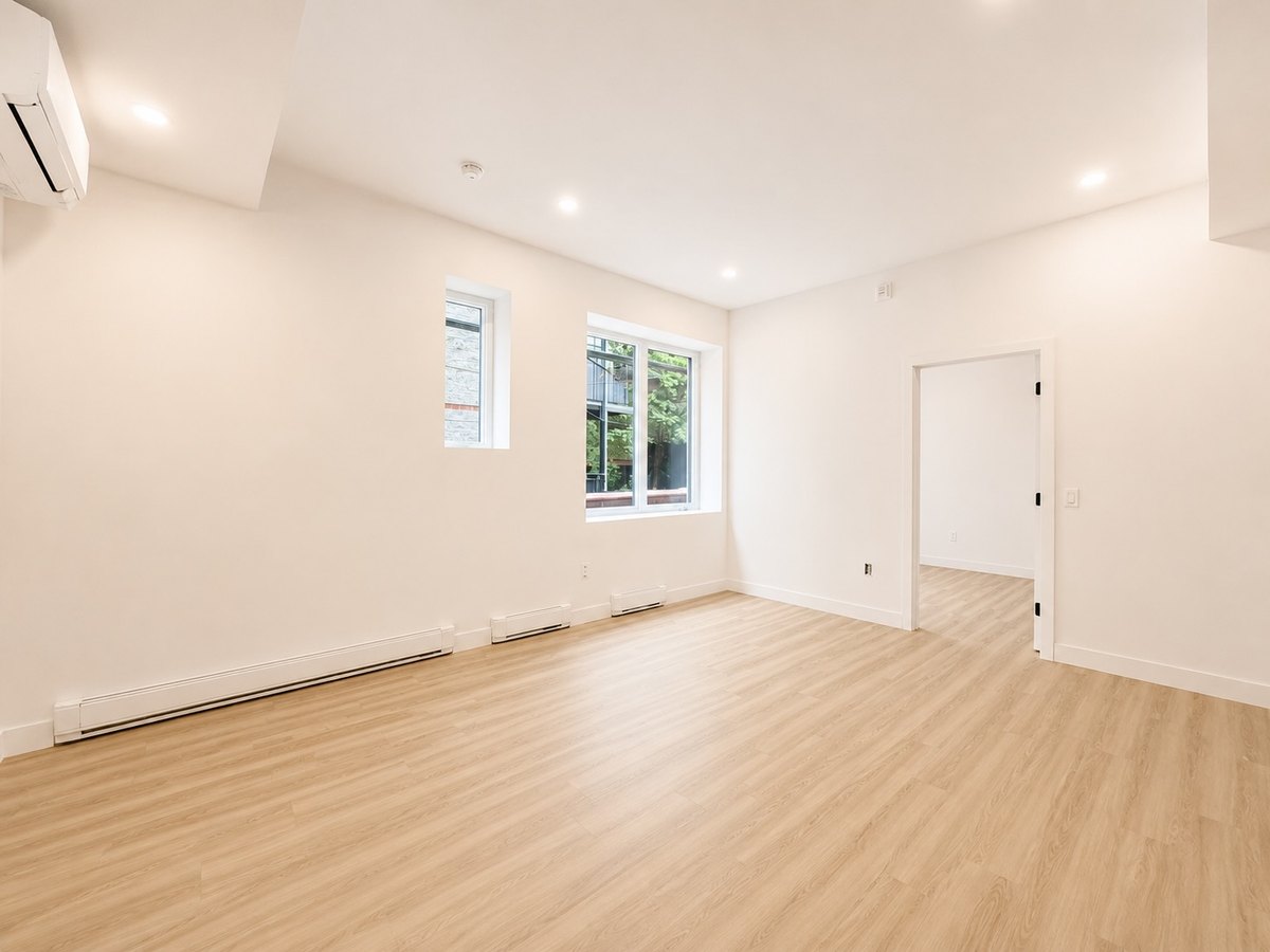 Rosemont : séjour non meublé avec deux fenêtres et plancher clair.